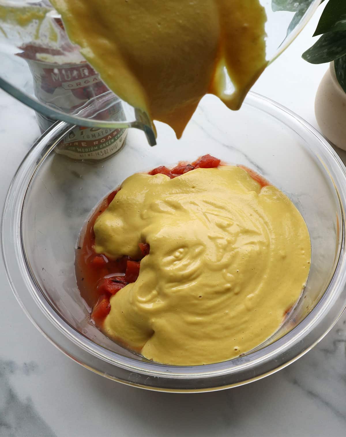 cashew sauce poured into a bowl of tomatoes.