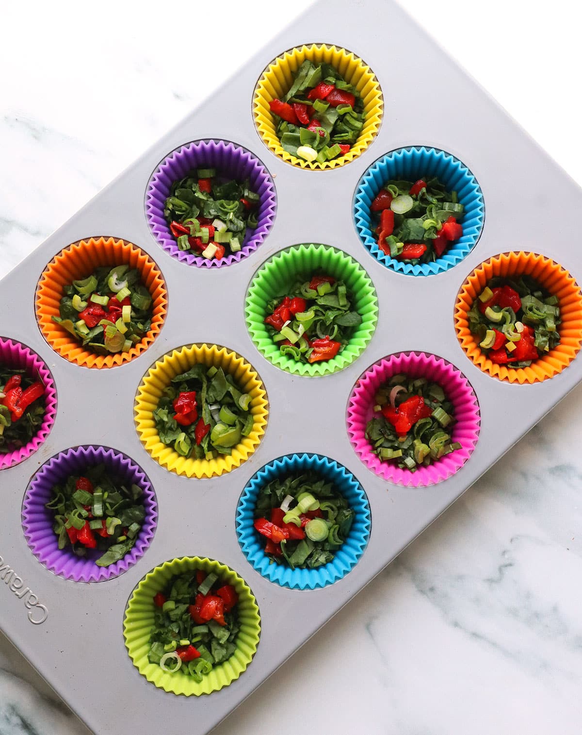 a muffin pan with silicone liners filled with veggies.