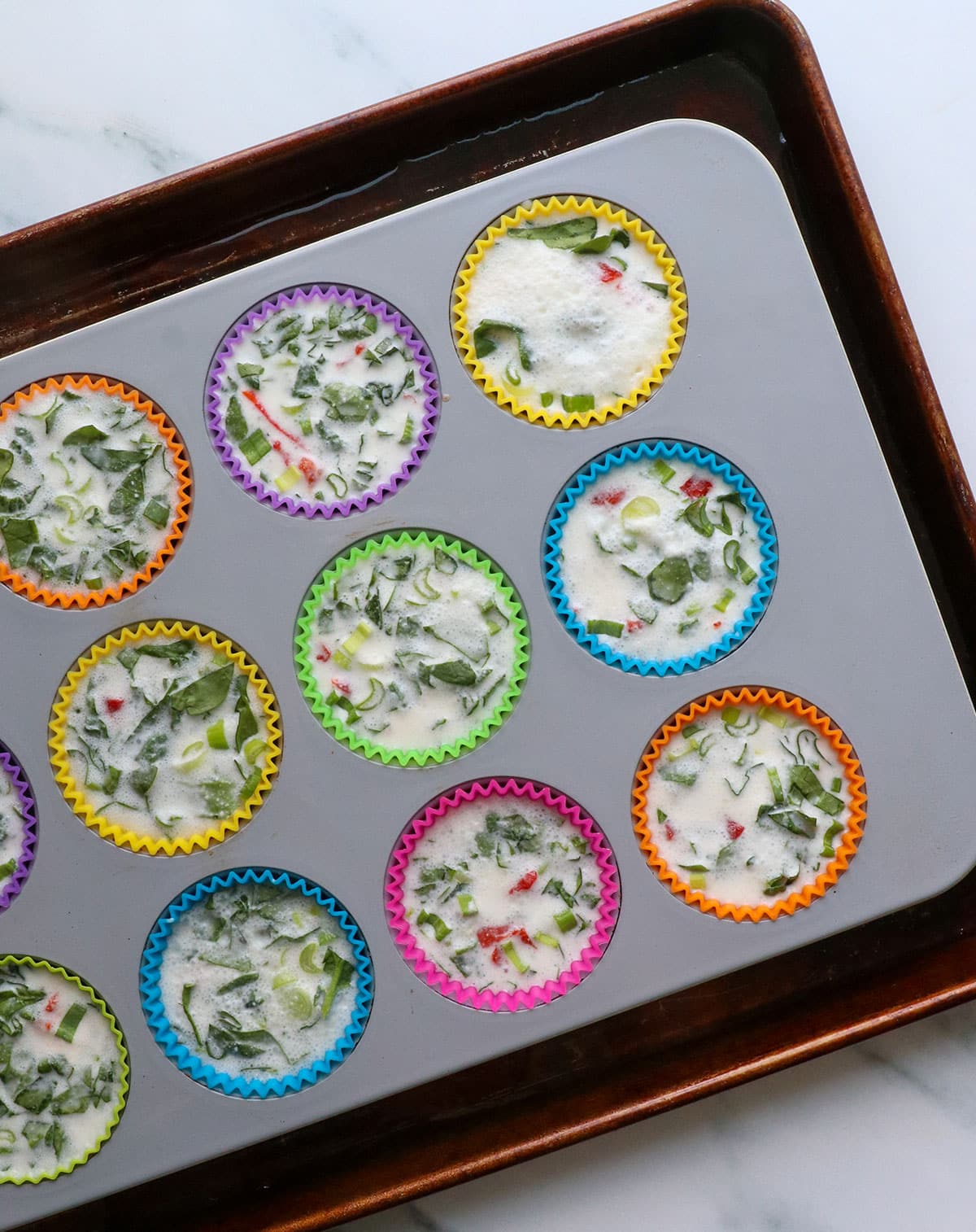 muffin pan of egg whites set into the rimmed baking sheet.