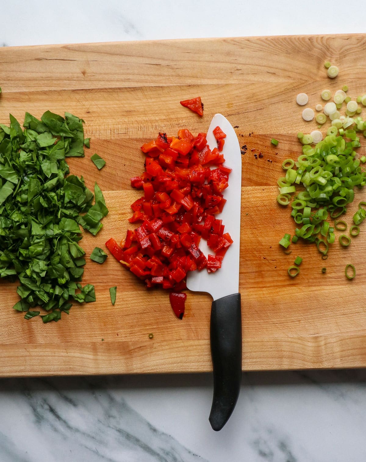 roasted red pepper, spinach, and green onion chopped on cutting board.