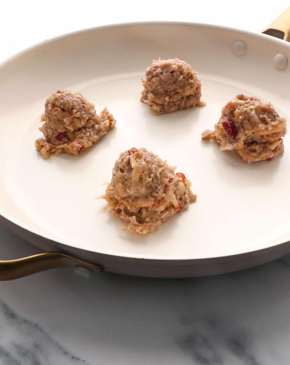chicken sausage scooped onto a white skillet, 4 at a time.
