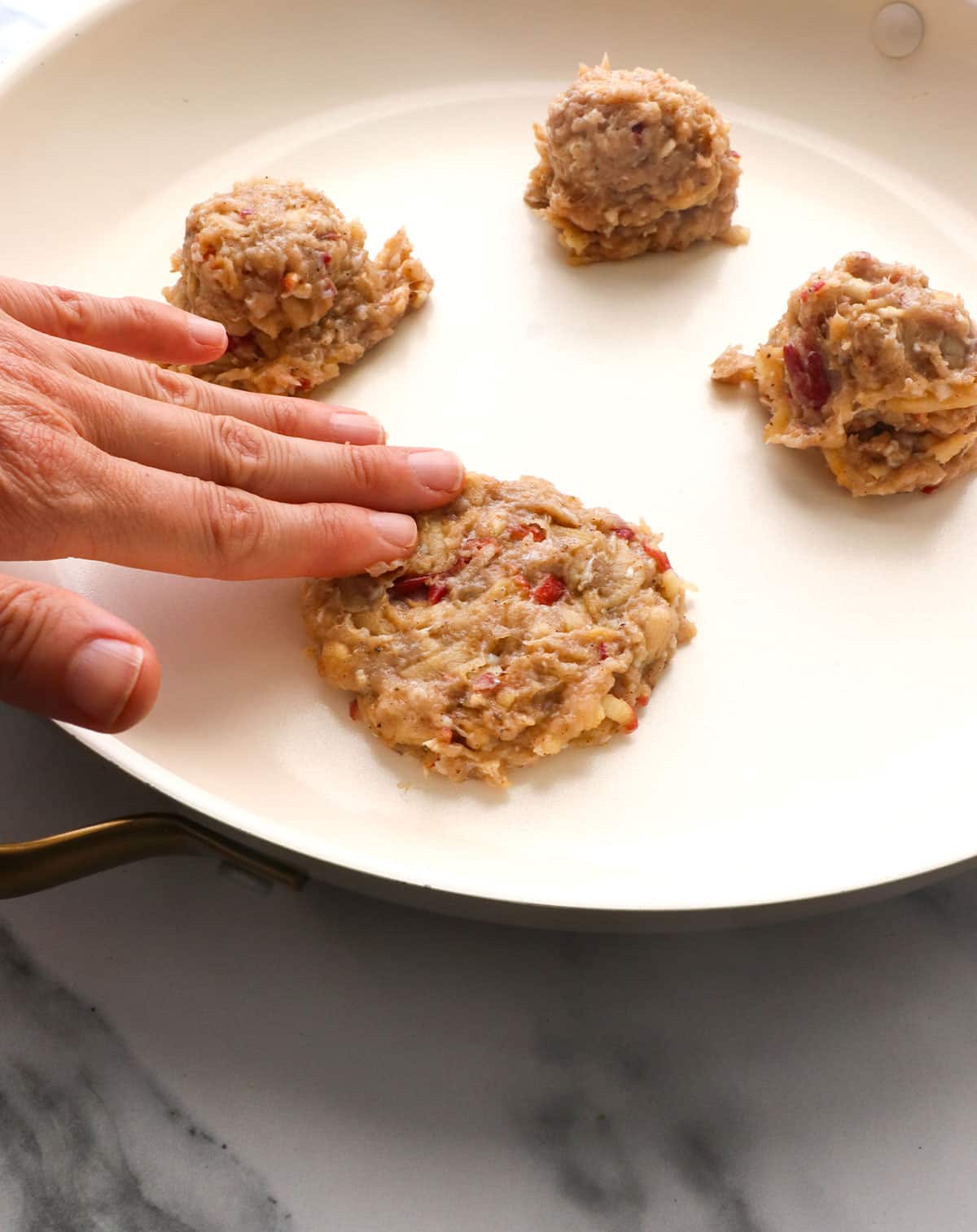 fingers flattening the scoop of chicken into a patty shape.