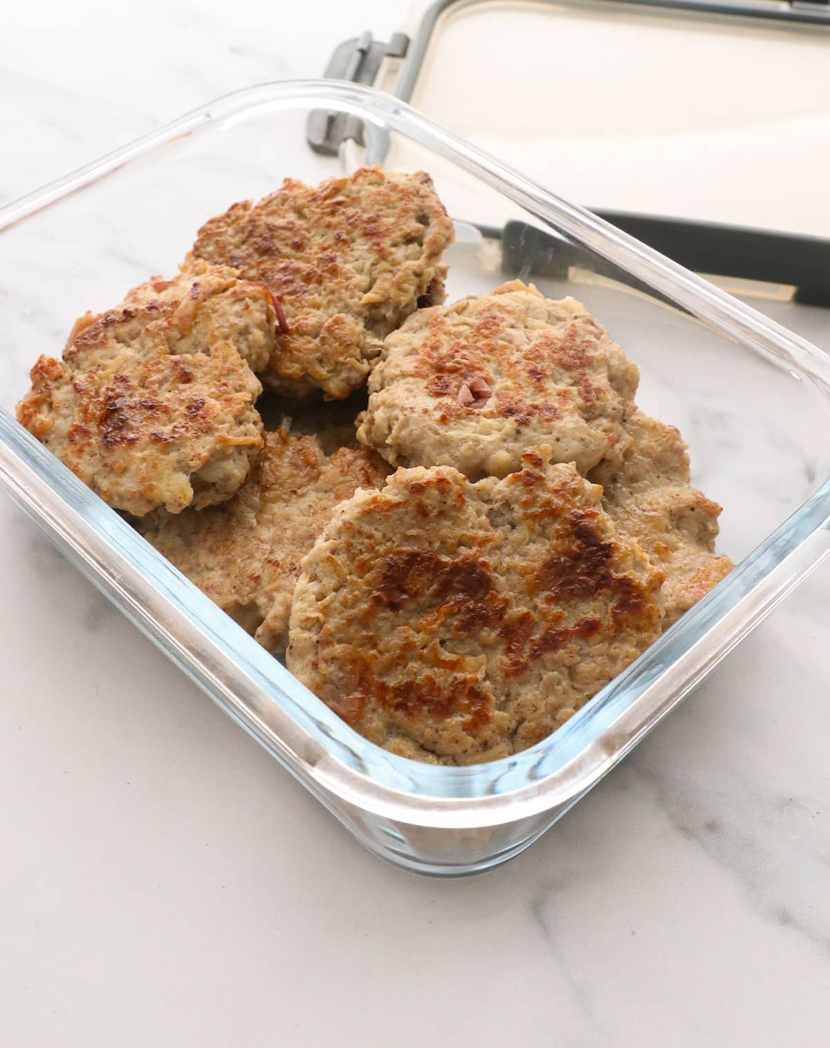 chicken apple sausage in a glass storage container near the lid.