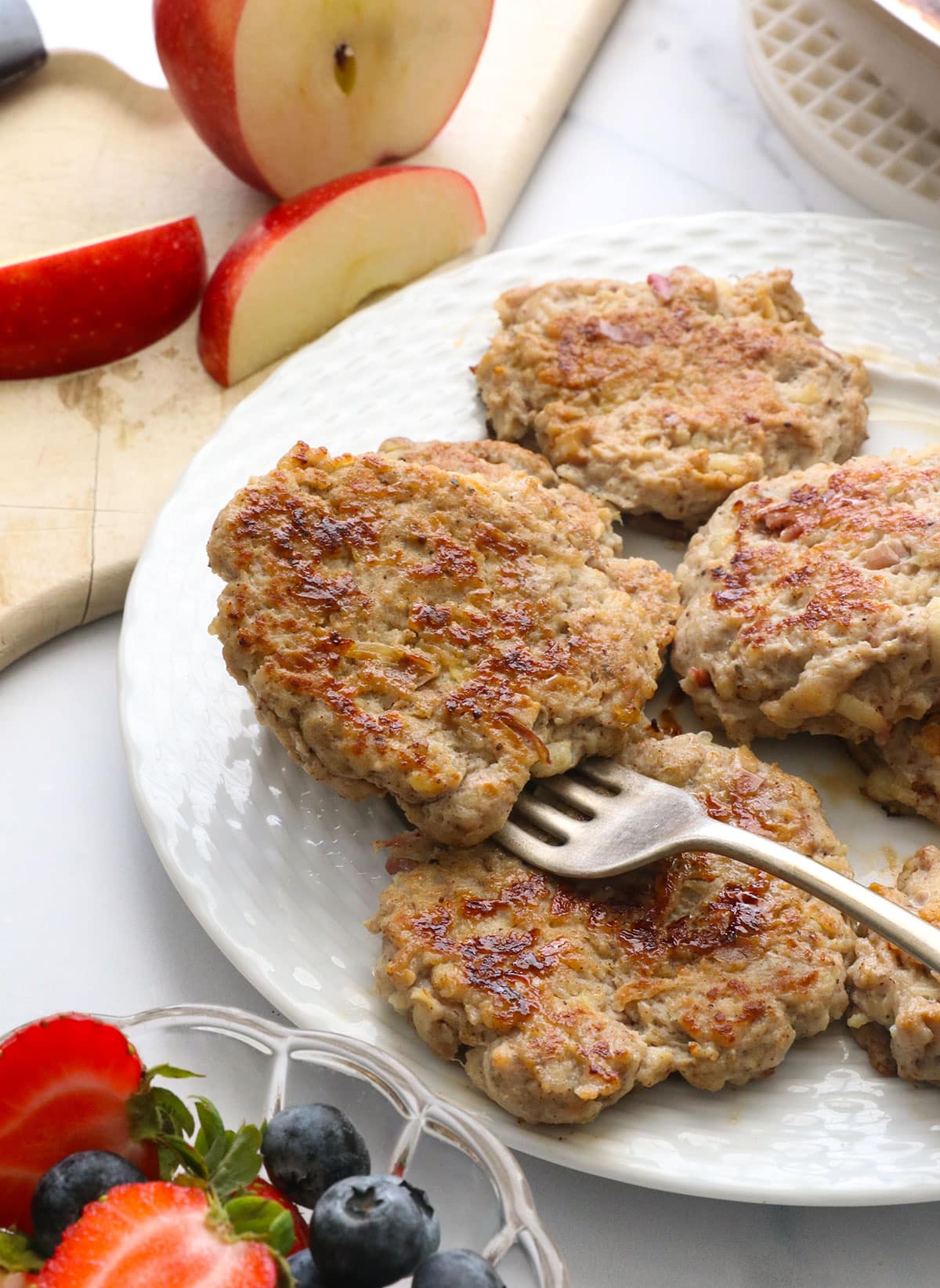chicken apple sausage patty sitting on a fork on a serving plate.