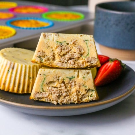 dairy free egg bites with italian sausage stacked on a dark plate.