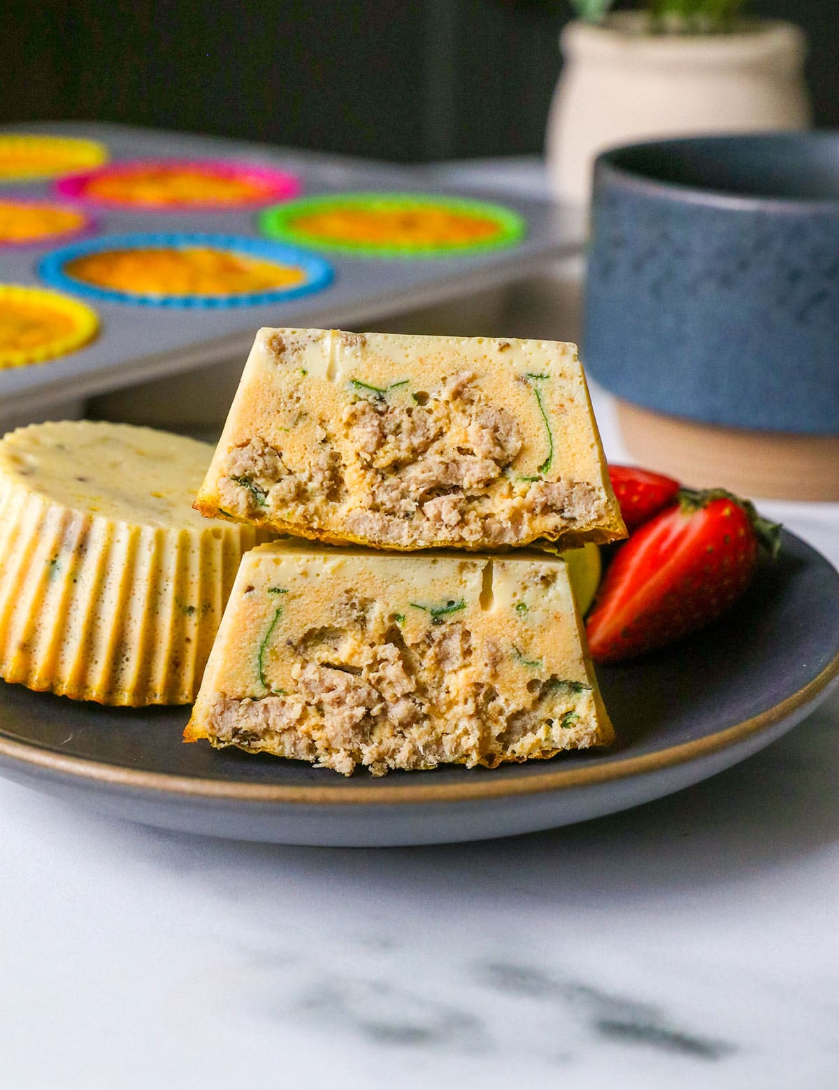dairy free egg bites with italian sausage stacked on a dark plate.