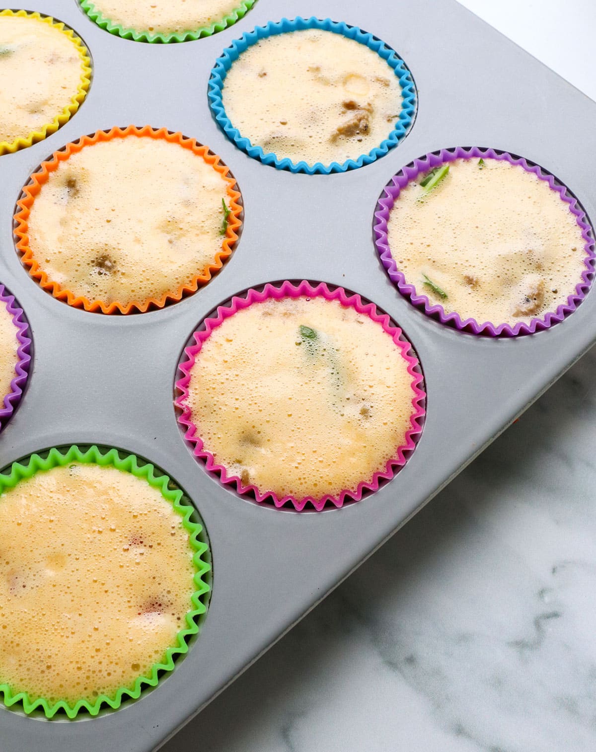 Muffin pan filled with sausage and egg mixture.