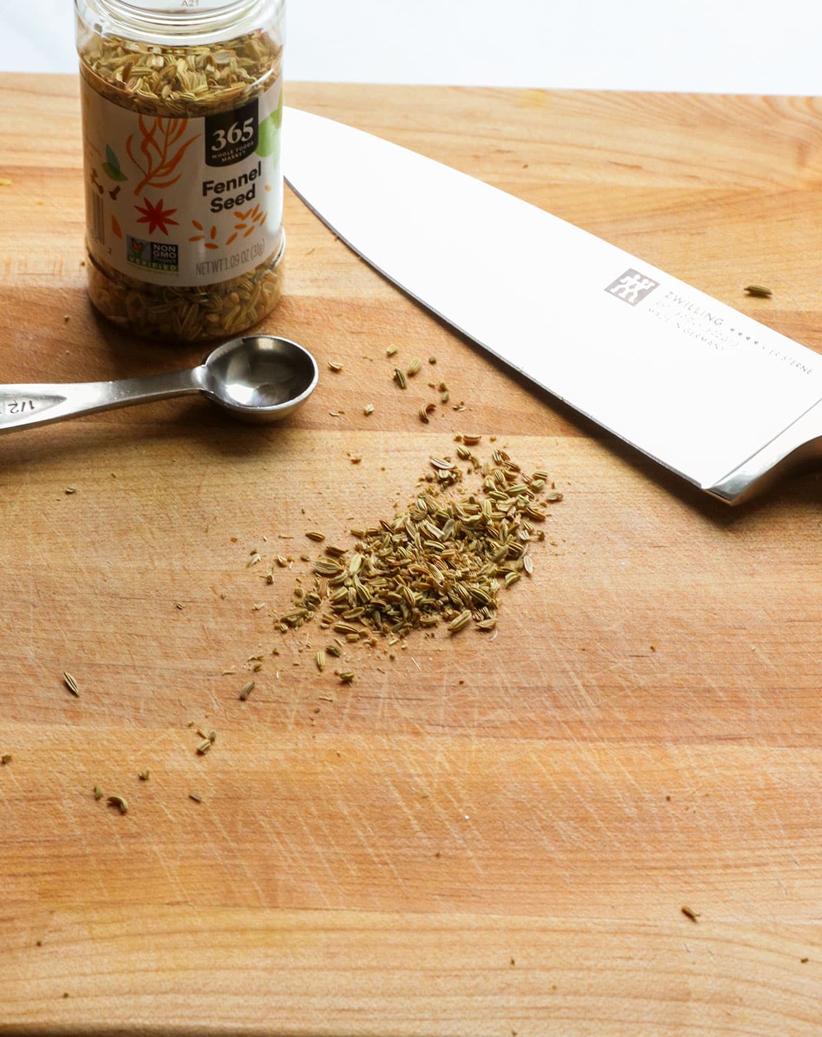fennel seeds on a cutting board with a sharp knife.