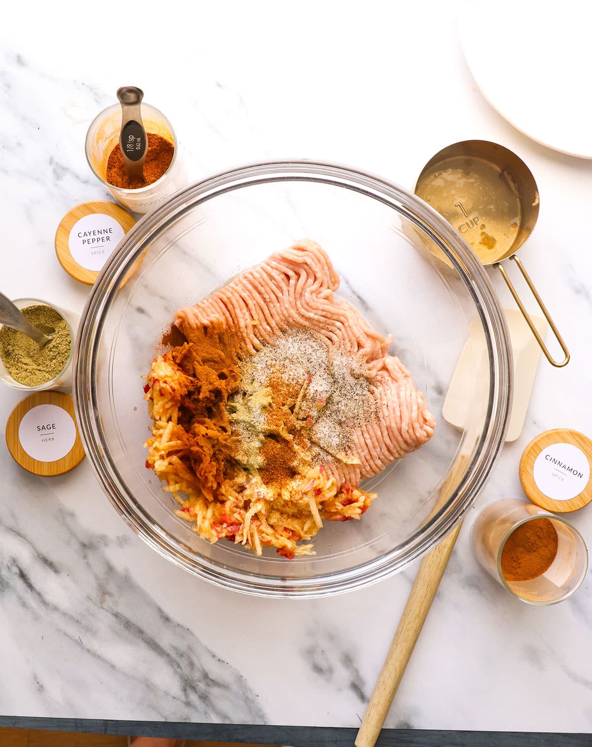 glass bowl with ground chicken, shredded apples, and pantry spices.