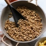 ground turkey sausage in a skillet with a dark spatula.