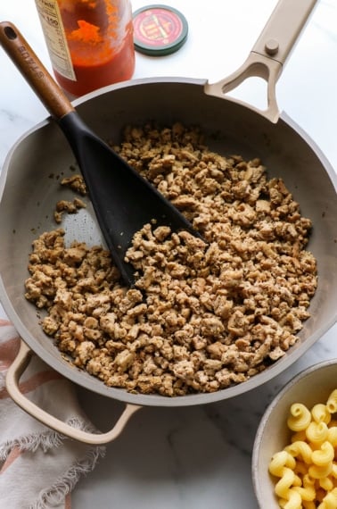 ground turkey sausage in a skillet with a dark spatula.