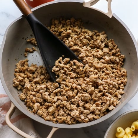 ground turkey sausage in a skillet with a dark spatula.